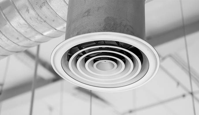 A ceiling diffuser hangs from a duct for ventilation