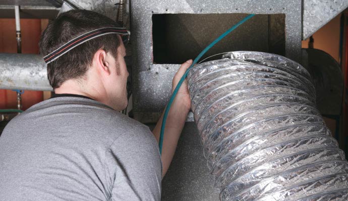 A technician is cleaning an air duct