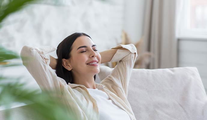 A woman relaxes on a sofa enjoying clean air