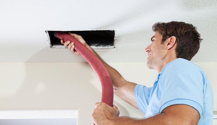 A professional cleaning HVAC ceiling air vent with equipment