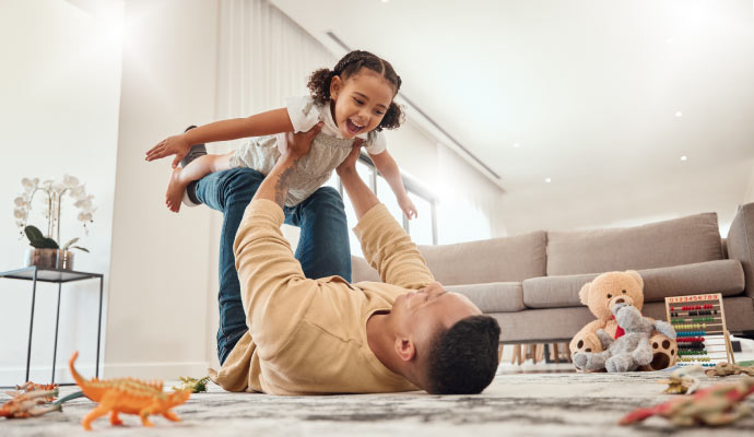 father playing with his child in a clean living room
