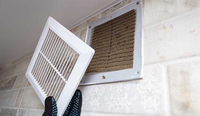 man removing dirty ventilation air cleaning grille at home close up