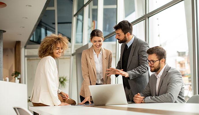 Professionals collaborating around a laptop in a modern office.