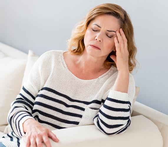 Woman sitting on sofa with a headache